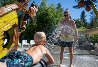 Child sprays water at adult at a fun splash park in De Thijmse Berg holiday park, Utrecht, Netherlands.