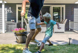 Padre e figlio giocano a calcio sul prato davanti a una casa vacanza al De Thijmse Berg, Utrecht, Paesi Bassi.