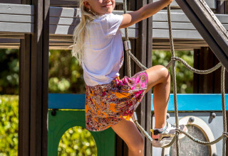 A blonde girl climbs a rope structure at the De Thijmse Berg holiday park playground in Utrecht, Netherlands.
