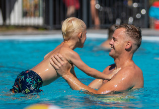 Padre e figlio che giocano in piscina al parco vacanze De Thijmse Berg, Utrecht, Paesi Bassi, sotto il sole.