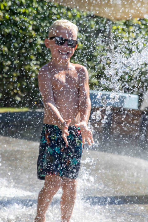 Ragazzo con occhiali da sole gioca con gli spruzzi d'acqua al parco vacanze De Thijmse Berg a Utrecht, Olanda.