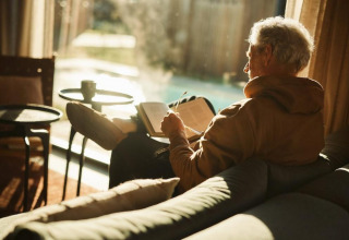 Hombre mayor relajándose y leyendo en Unbrick One | Sauna and Pool, Brinckerduyn, Países Bajos.