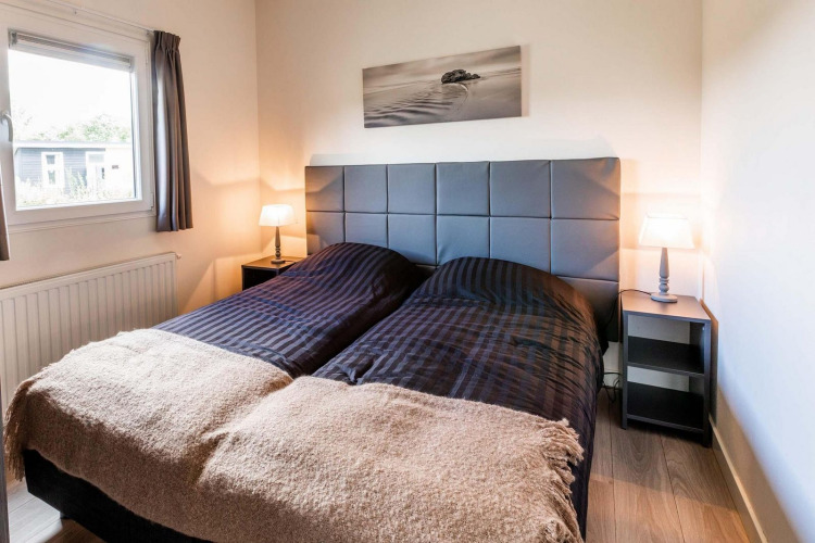 Gemütliches Schlafzimmer mit zwei Einzelbetten, gepolstertem Kopfteil und Lampen im Berkenhoeve, Niederlande.