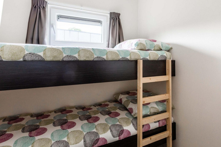 Etagenbett mit gemustertem Bettzeug und Fenster bei Berkenhoeve, Résidence Lichtenvoorde, Niederlande.