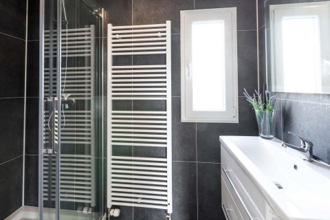 Baño moderno con ducha, radiador toallero, ventana y lavabo en Berkenhoeve, Résidence Lichtenvoorde.