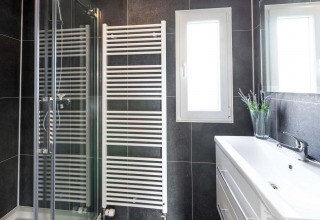 Baño moderno con ducha, radiador toallero, ventana y lavabo en Berkenhoeve, Résidence Lichtenvoorde.