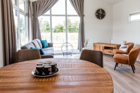 Moderno soggiorno nel lodge Berkenhoeve a Résidence Lichtenvoorde, Paesi Bassi, con ampie finestre e arredi.