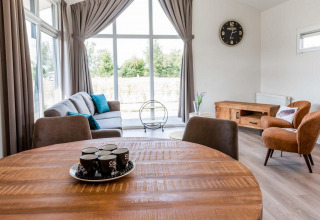 Moderno soggiorno nel lodge Berkenhoeve a Résidence Lichtenvoorde, Paesi Bassi, con ampie finestre e arredi.