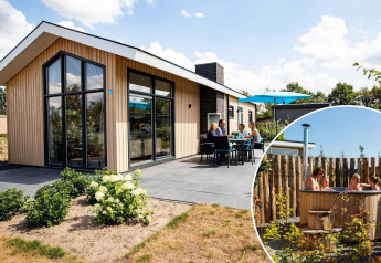 Moderne lodge Berkenhoeve Wellness met terras en gasten die genieten in een privé hot tub buiten.