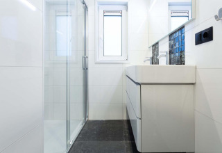 Modern bathroom with glass shower, large sink, and window at Berkenhoeve Wellness, Résidence Lichtenvoorde.