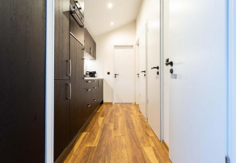 Pasillo moderno con suelo de madera, puertas blancas y cocina oscura en Berkenhoeve Wellness, Résidence Lichtenvoorde.