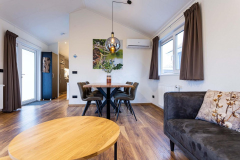 Moderne woonkamer in Berkenhoeve Wellness Lodge, Résidence Lichtenvoorde, met houten vloer en comfortabele stijl.