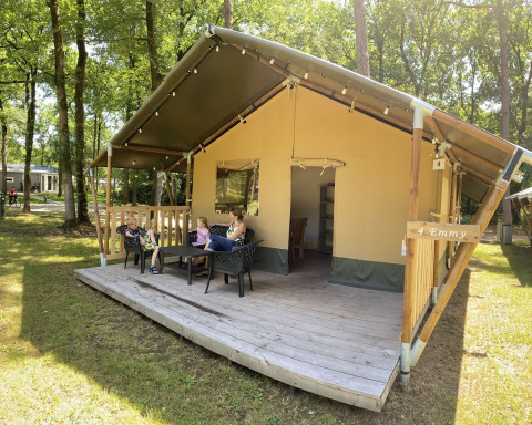 Tenda safari al Holiday Park Bonte Vlucht nei Paesi Bassi con famiglia che si rilassa sulla veranda.