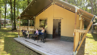 Tienda safari en Holiday Park Bonte Vlucht en los Países Bajos con familia descansando en la terraza.