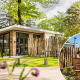 Moderne lodge Silva Wellness med privat udendørs hot tub ved Bospark Ede, omgivet af grønt i Holland.