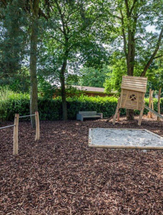 Aire de jeux avec bac à sable, balançoire, cabane et toboggan dans Bungalowpark Het Verscholen Dorp, Pays-Bas.