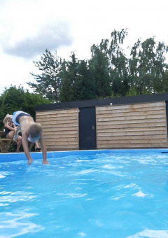 Niños juegan junto a la piscina de un parque de vacaciones con valla de madera en Gelderland, Países Bajos.