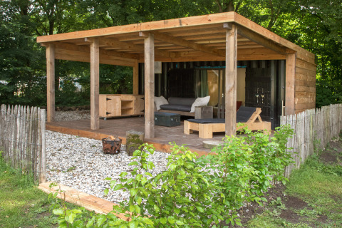Zona relax esterna della tiny house ‘Sea container’ con terrazza in legno, sedute e recinto naturale.