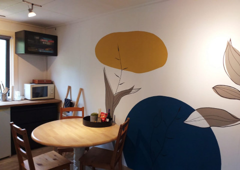 Salle à manger d'une tiny house à Buytenplaets Suydersee, Pays-Bas, avec fresque colorée et table en bois.