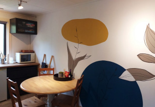 Salle à manger d'une tiny house à Buytenplaets Suydersee, Pays-Bas, avec fresque colorée et table en bois.