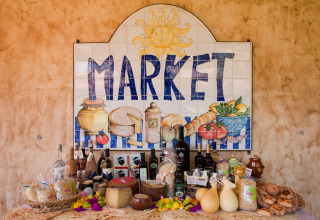 Market sign with Sardinian products like cheese, wine, and bread at Centro Vacanze Isuledda holiday park.