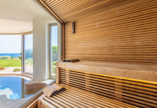 Sauna moderna de madera con vistas panorámicas al jardín y al mar en Centro Vacanze Isuledda, Cerdeña.