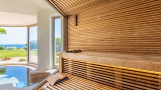 Sauna moderna de madera con vistas panorámicas al jardín y al mar en Centro Vacanze Isuledda, Cerdeña.