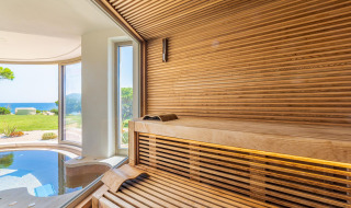 Sauna moderna de madera con vistas panorámicas al jardín y al mar en Centro Vacanze Isuledda, Cerdeña.