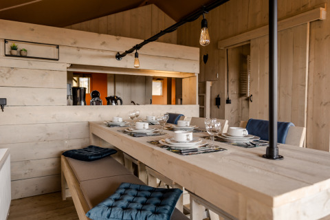 Acogedor comedor de Glamping Lodge en Camping Waddenzee, Países Bajos, con decoración de madera rústica.