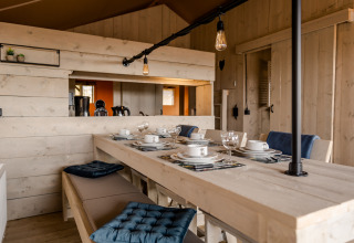 Inviting dining area at Glamping Lodge, Camping Waddenzee, Netherlands, featuring rustic wooden décor.