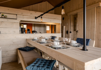 Indbydende spiseområde i Glamping Lodge på Camping Waddenzee, Holland, med rustik træindretning.