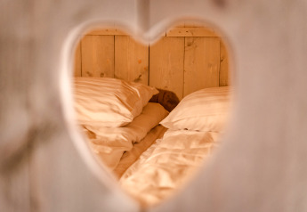 Vue à travers une découpe en cœur sur un lit douillet à Glamping Lodge au Camping Waddenzee, Pays-Bas.