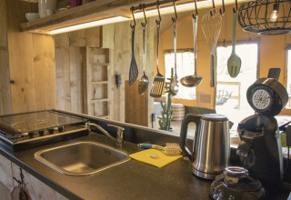 Modern kitchen area at Glamping Lodge, Camping Waddenzee, Netherlands, featuring utensils and appliances.