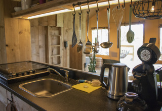 Cocina moderna en Glamping Lodge, Camping Waddenzee, Países Bajos, con utensilios y electrodomésticos.
