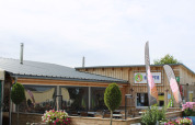 Receptionen og udendørs siddeområde ved Camping Oos Heem feriepark i Liège, Belgien på en solrig dag.