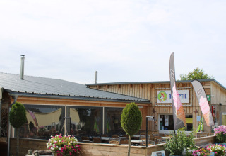 Reception and outdoor seating area at Camping Oos Heem holiday park in Liège, Belgium on a sunny day.