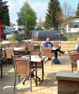 Gasten genieten van het terras bij Camping Oos Heem vakantiepark in Luik, België.