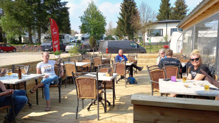Gasten genieten van het terras bij Camping Oos Heem vakantiepark in Luik, België.