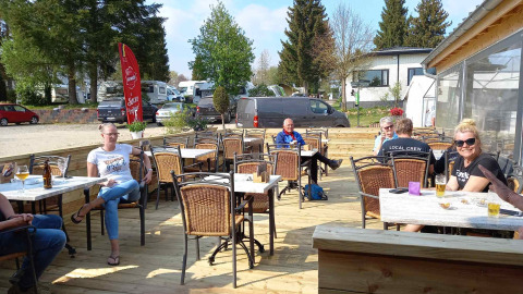 Guests relaxing outdoors on the sunny terrace at Camping Oos Heem holiday park in Liège, Belgium.