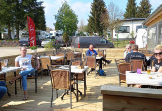 Ospiti che si rilassano sulla terrazza soleggiata del Camping Oos Heem a Liegi, Belgio.