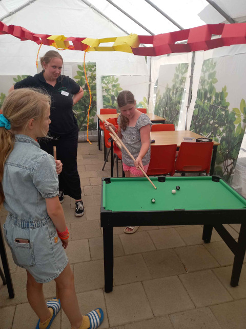 Niños juegan billar mini bajo una carpa en Camping Oos Heem, un parque vacacional en Lieja, Bélgica.