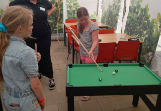 Kinder spielen Minibillard in einem Zelt im Camping Oos Heem, einem Ferienpark in Lüttich, Belgien.