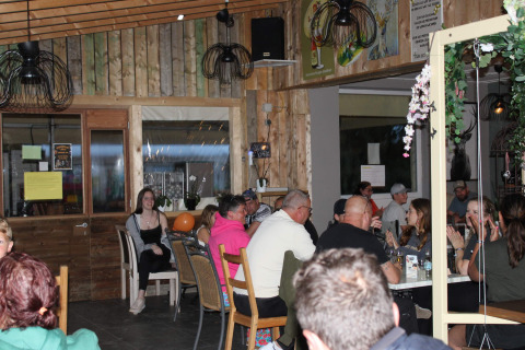Personas compartiendo y cenando en el restaurante del Camping Oos Heem, un parque vacacional en Lieja, Bélgica.