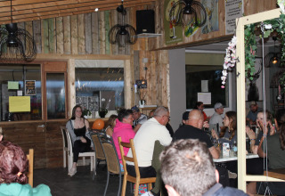 Persone che condividono un pasto nel ristorante del Camping Oos Heem, villaggio vacanze a Liegi, Belgio.