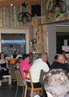 Personas compartiendo y cenando en el restaurante del Camping Oos Heem, un parque vacacional en Lieja, Bélgica.