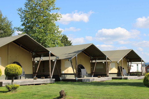 Fila di moderne tende glamping con veranda al Camping Oos Heem, parco vacanze a Liegi, Belgio, in una giornata di sole.