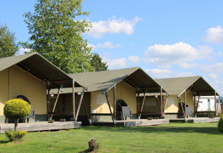 Fila di moderne tende glamping con veranda al Camping Oos Heem, parco vacanze a Liegi, Belgio, in una giornata di sole.