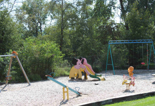 Parco giochi con scivolo, altalene e dondolo circondato da alberi presso Camping Oos Heem a Liegi, Belgio.