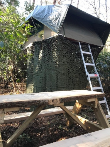 Casa del árbol Treelodge en Costa Kabrita, Países Bajos, con escalera y red de camuflaje en entorno natural.