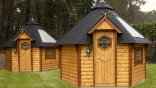 Two octagonal wooden tiny houses with black roofs at Finse Kota, Costa Kabrita, Netherlands, forest behind.